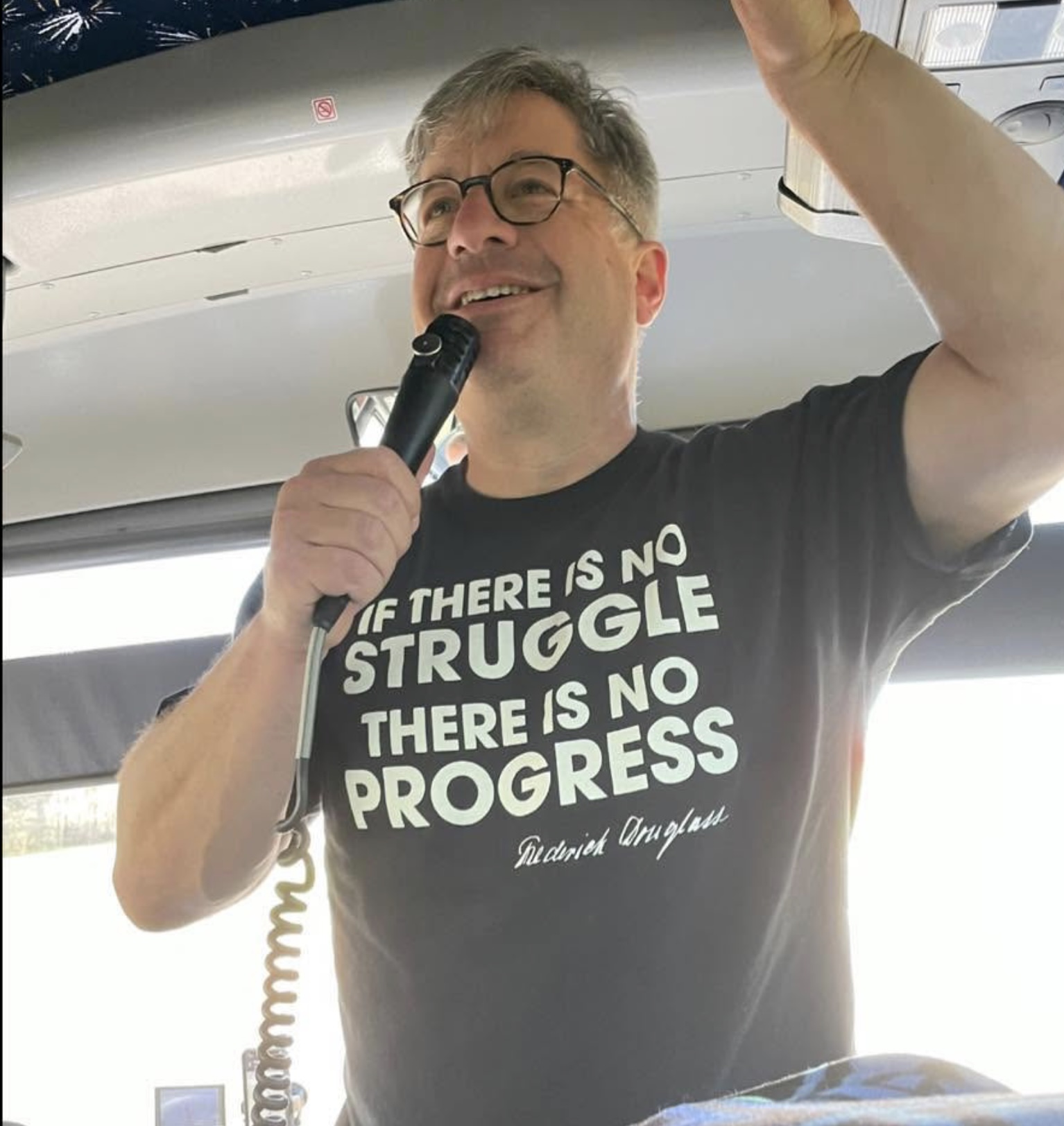 Billy Planer speaking on the microphone on a bus
