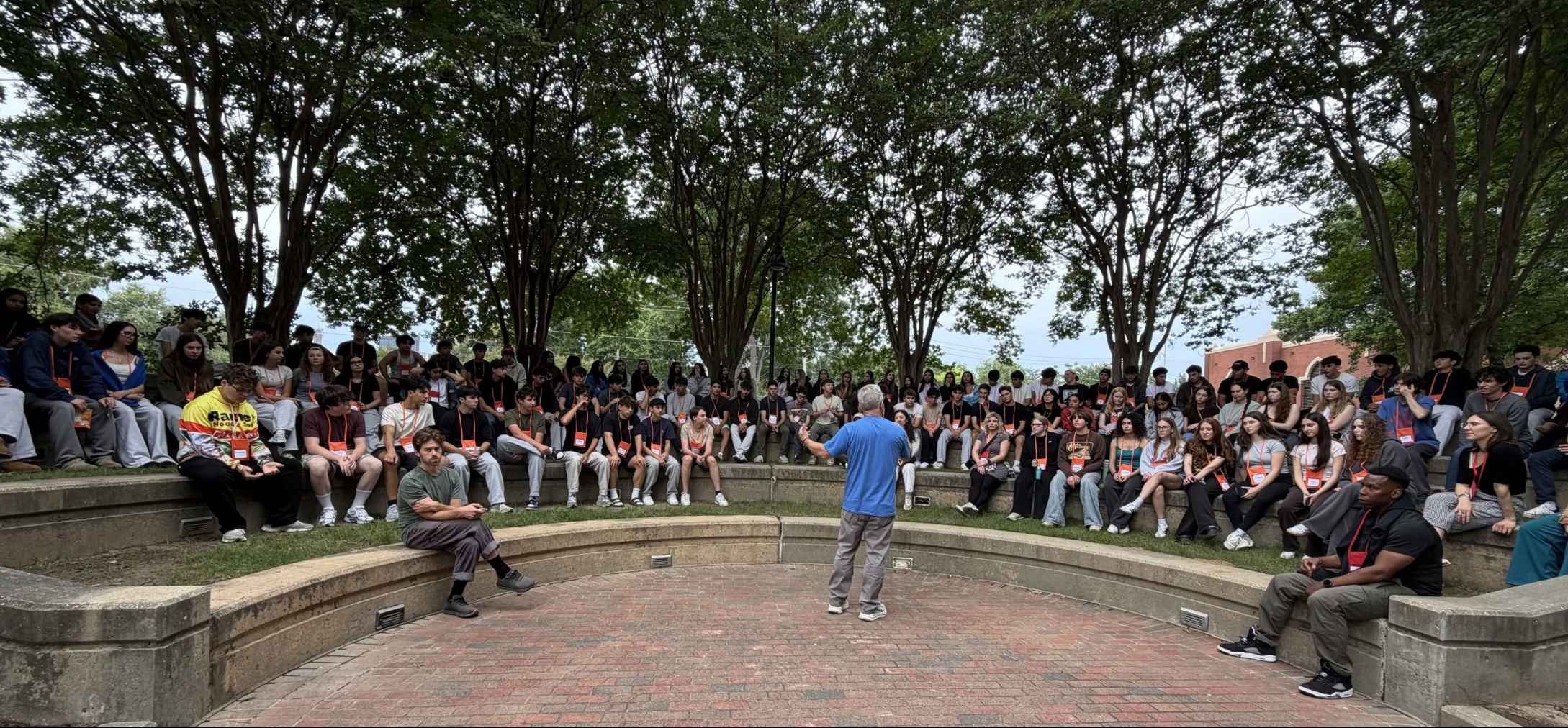 Billy Planer speaking to a large group of young people in an outdoor ampitheater